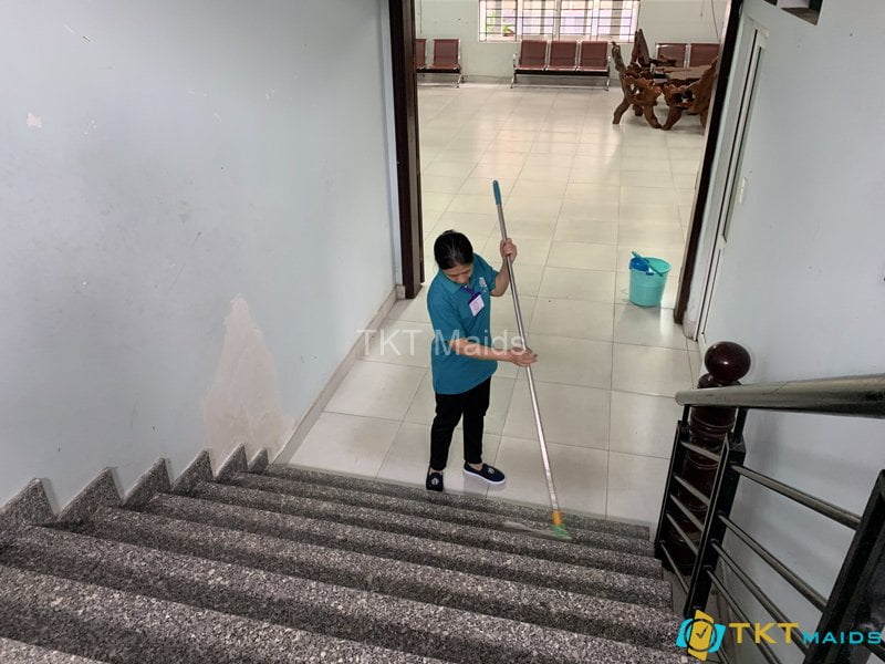 Nhân viên tạp vụ lau sàn cầu thang bộ trong trường học