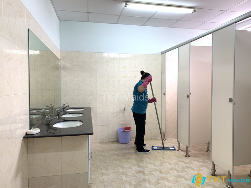 Tạp vụ lau chùi sàn trong nhà vệ sinh 